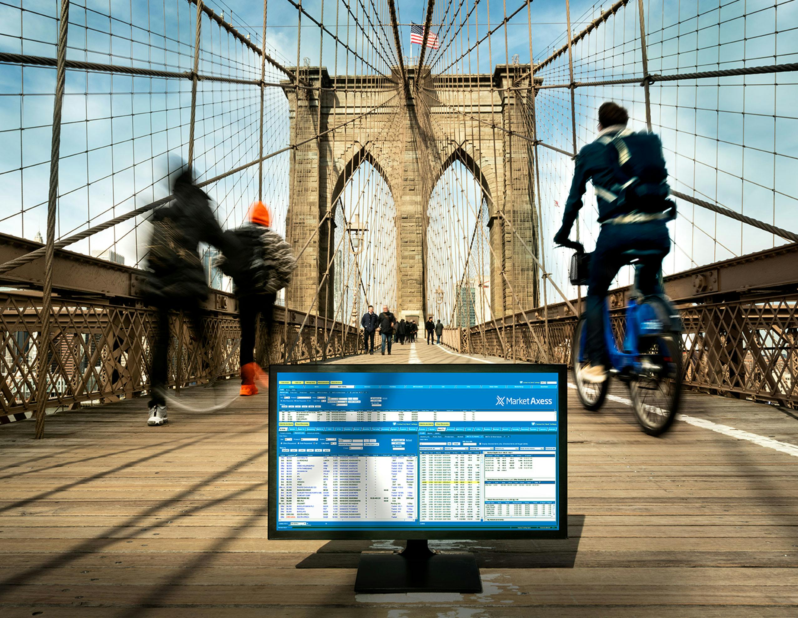 Computer monitor sitting on the Brooklyn Bridge bike path with bikers and joggers going past